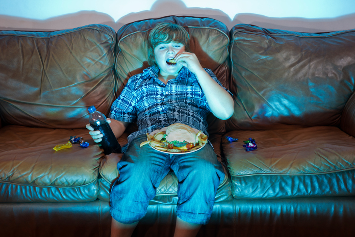 Child eating unhealthy snacks while watching TV