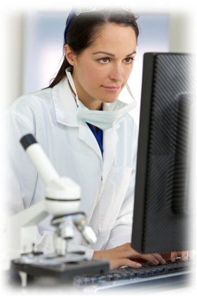 Lab worker looking at a computer with a microscope in the foreground
